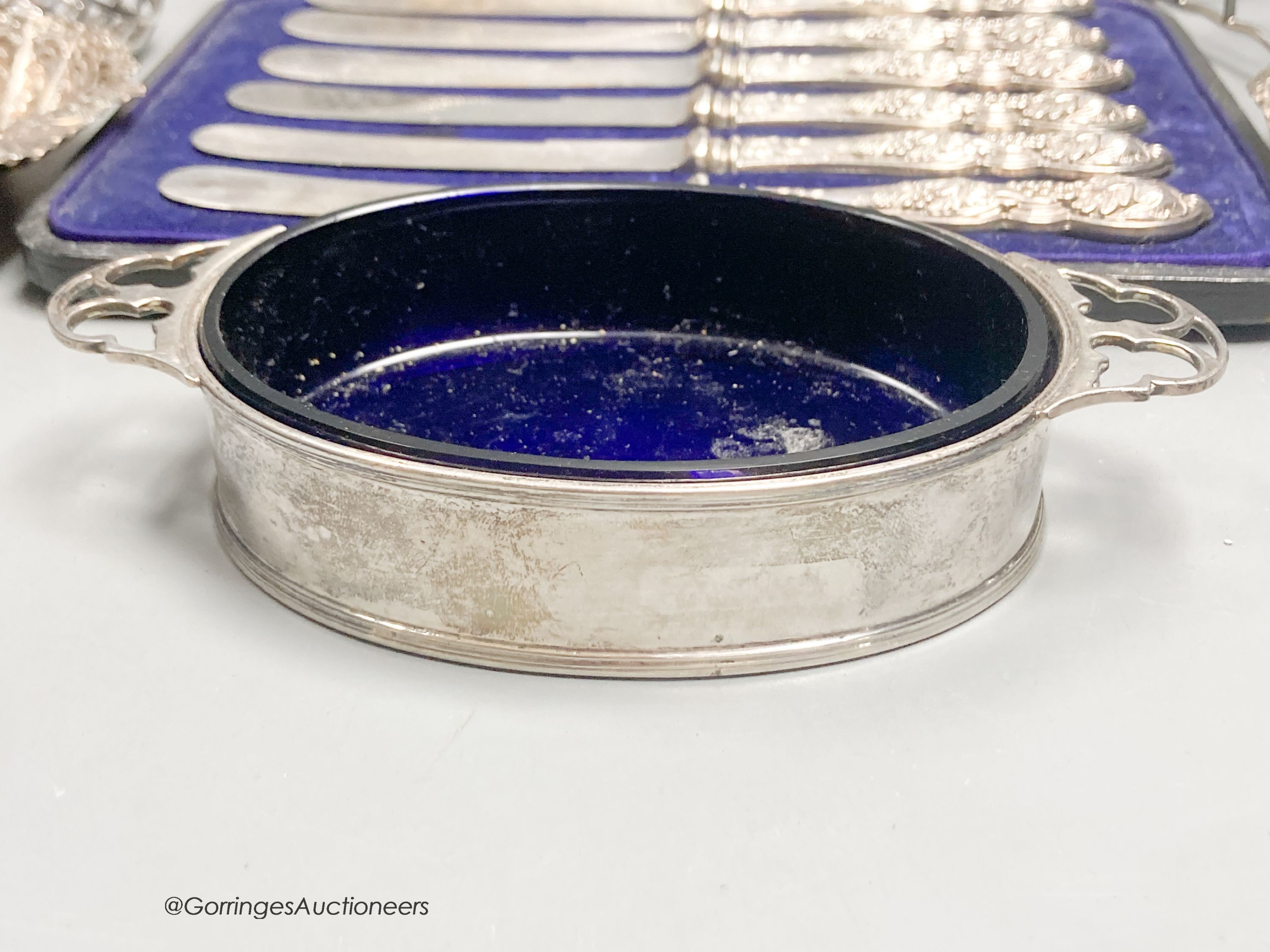 A George V silver two handled butter dish, with blue glass liner, a white metal basket, a pair of Victorian shell dishes, a French white metal dish, white metal toast rack and cased tea knives.